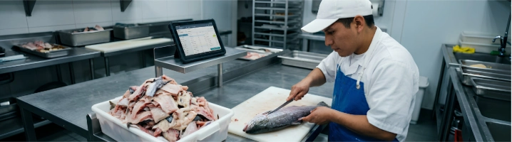 Cocinero fileteando pescado con exceso de merma sin registrar en el software del restaurante